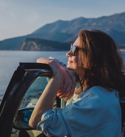 Relaxed woman leaning against car